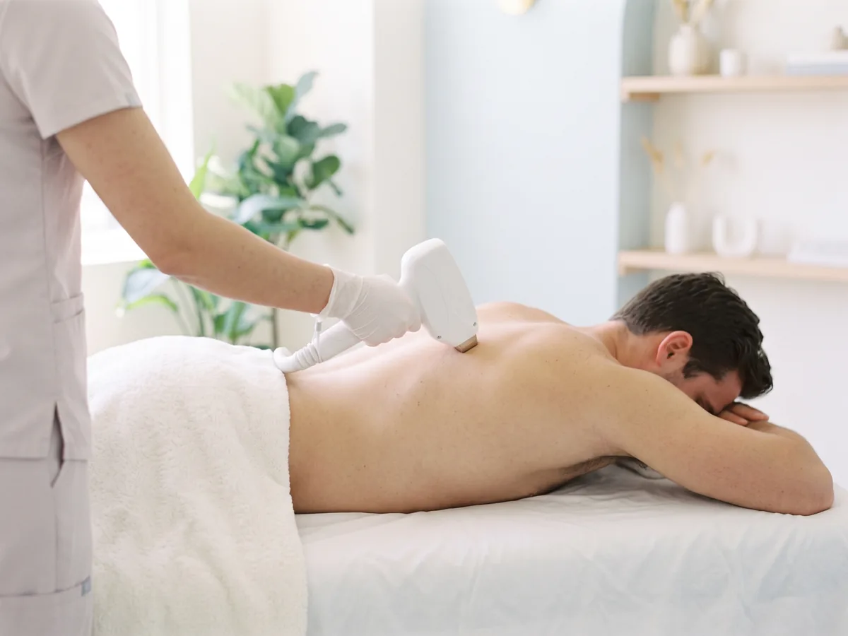 A man lying face down having laser hair removal on his upper back
