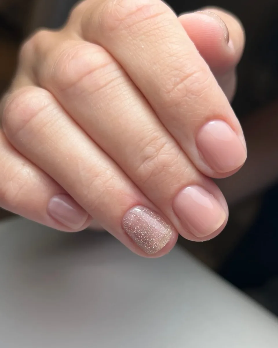 A soft nude manicure with one glitter nail